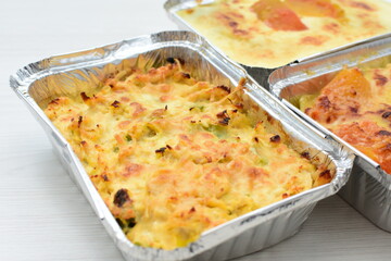 Baked chicken and mushroom cannelloni, bathed in cream in cheese sauce gratin on white wooden background