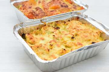 Baked chicken and mushroom cannelloni, bathed in cream in cheese sauce gratin on white wooden background