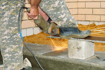 the worker holds a disk grinder in his hands and cuts metal, hot sparks fly