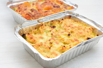 Baked chicken and mushroom cannelloni, bathed in cream in cheese sauce gratin on white wooden background