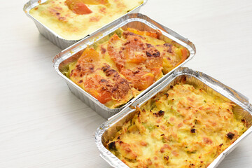 Baked chicken and mushroom cannelloni, bathed in cream in cheese sauce gratin on white wooden background