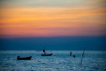 silhouette of fishing boats against sunset