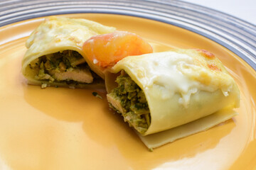 Baked chicken and mushroom cannelloni, bathed in cream in cheese sauce gratin on white wooden background