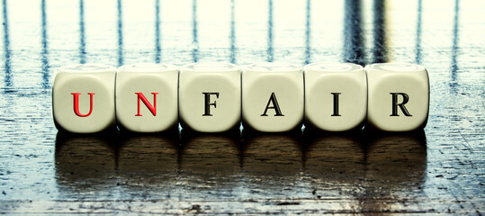 Concept of dices with letters forming word "Unfair" or "fair" 