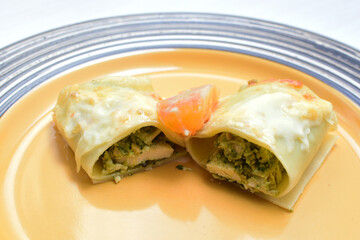 Baked chicken and mushroom cannelloni, bathed in cream in cheese sauce gratin on white wooden background