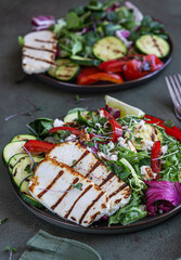 Grilled halloumi cheese with grilled vegetables and green salad, green concrete background. Healthy food concept.
