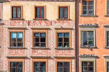 Fototapeta na wymiar Warsaw, Poland old town market square rynek with historic architecture of wall with windows closeup pattern of red orange yellow color
