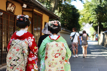 Fototapeta premium Two geisha in traditional Japanese costumes stroll along Kyoto street 