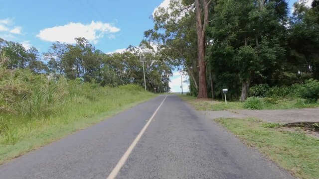 Rear facing driving point of view POV of a deserted and dead straight Queensland country lane in the Glasshouse Mountains - ideal for interior car scene green screen replacement