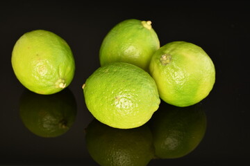 Several ripe limes, close up, on a black background.