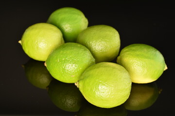 Several ripe limes, close up, on a black background.