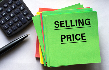 SELLING PRICE - text on a green note sheet against the background of a calculator and a pen