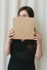 Fototapeta premium Beautiful young woman in a black dress with a box in her hands. The concept of style, elegance, fashion.
