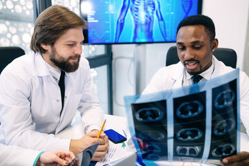 Fototapeta premium Two doctors look at x-rays and discuss the diagnosis. They sit a