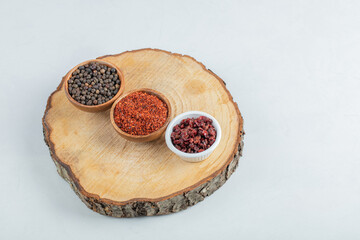 Many bowls of spices on a wooden piece