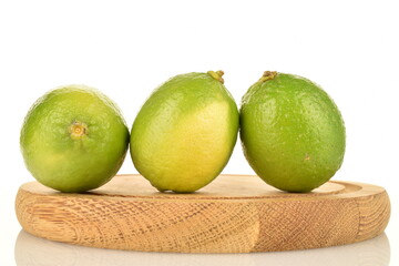 Three natural limes on a bamboo tray, close-up, on a white background.