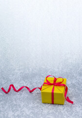 Gray background. Yellow gift box with red ribbon. Yellow box color