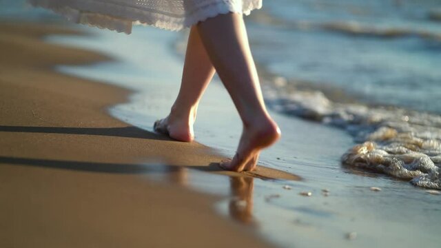 Pretty woman walks at seaside surf. Woman in white dress resting on the sea