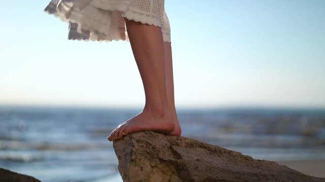 Female feet standing on a stone on the bech. Woman on the stony beach on the sea