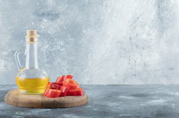 Obraz premium Sliced of sweet bell red pepper with a glass bottle of oil on a wooden board