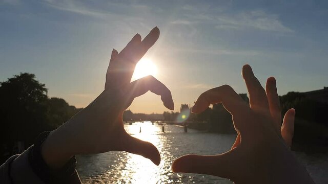 Hands making heart shape over Paris cityscape