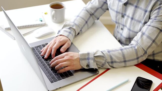 A man works with a laptop, types text on the keyboard, working office