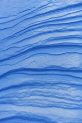 Wavy layers of glistening snow, illuminated by the winter sun in the evening. The surface of the ground is covered with snow. An imprint of a frozen blizzard in Scandinavia.