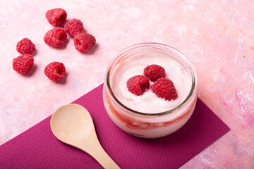 Healthy breakfast.Glass jar with organic yogurt and fresh raspberries on a textured background