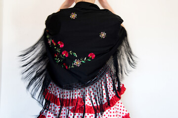 Hermosa mujer española con traje rojo de flamenca y mantón de manila negro bordado con flores. Bailando, en movimiento. Concepto de bailaora de sevillanas. Flamenco - obrazy, fototapety, plakaty