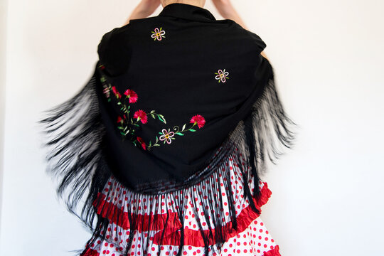 Hermosa mujer espa&ntilde;ola con traje rojo de flamenca y mant&oacute;n de manila negro bordado con flores. Bailando, en movimiento. Concepto de bailaora de sevillanas. Flamenco