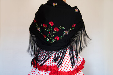 Hermosa mujer española con traje rojo de flamenca y mantón de manila negro bordado con flores. ....