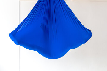 Work out on a hammock with a great yoga coach in the studio. Fly yoga. A girl lies in a blue anti-gravity yoga hammock in shavasana.