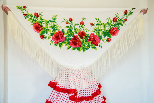 Hermosa mujer espa&ntilde;ola con traje rojo de flamenca sujetando un mant&oacute;n de manila blanco con flores. Concepto de bailaora de sevillanas. Flamenco