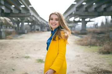 young girl in a yellow coat at an abandoned construction site. city ​​landscape.