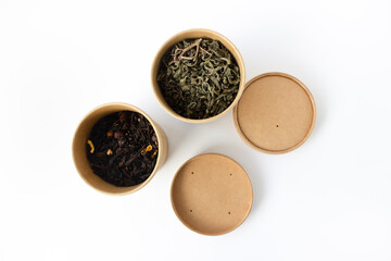 Green and black tea in reusable round cardboard packaging isolated on white background. View from above.