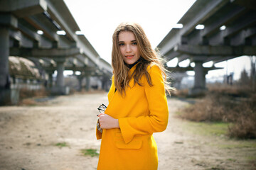 young girl in a yellow coat at an abandoned construction site. city ​​landscape.