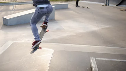 Tapeten Unrecognizable skateboarder doing olie jump in skatepark © marritch