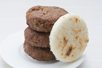 Seasoned meatloaf served with corn arepa on white wooden background