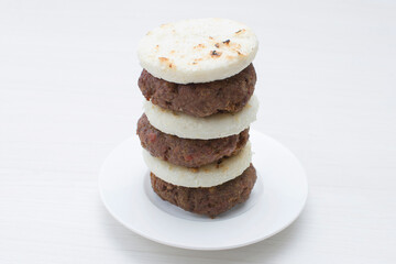 Seasoned meatloaf served with corn arepa on white wooden background