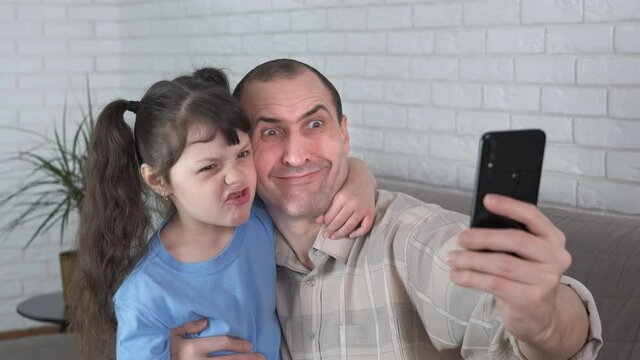 Funny photo on a smartphone. Daughter and dad make scary faces and take pictures on the phone.