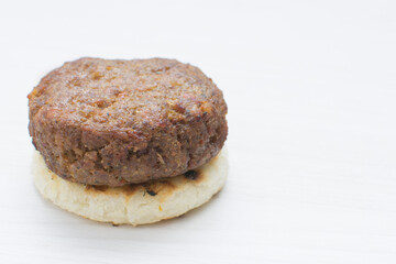 Seasoned meatloaf served with corn arepa on white wooden background