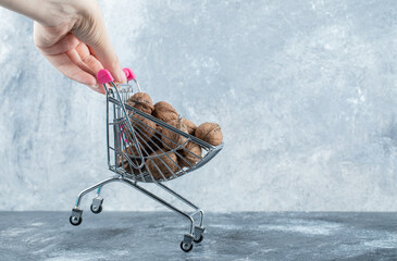 A small cart full of healthy walnuts on a gray background
