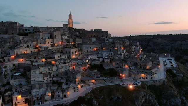 sassi di matera old town aerial view drone at sunrise flying orbit,historic city skyline illuminated at dawn twilight