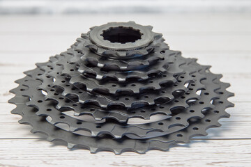 A new black bicycle cassette sits on a wooden background