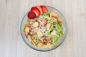 Chicken salad, strawberries, Parmesan cheese, lettuce and tomato in glass container
