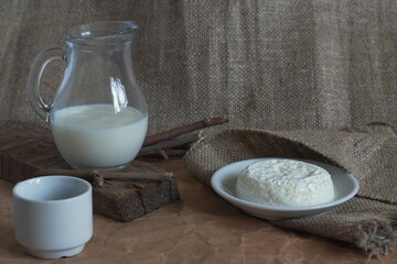 Homemade cheese and carafe with rustic milk on the table and textiles
