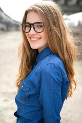 young female student in a blue shirt posing on the street on a sunny day.