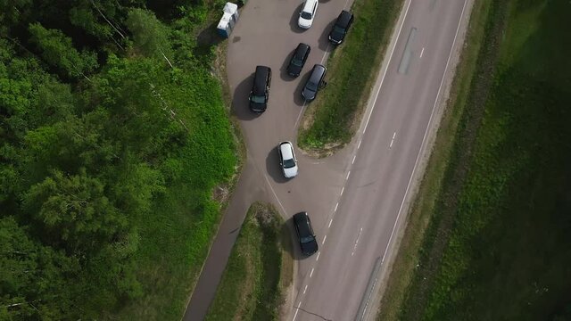 Aerial top down view of car driving on country road. Drone shot flying over fields, trees. High quality 4k footage