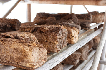 Chunks of peat piled up for drying on wooden shelf . Horizontal photo with blurred front and background. Peat production