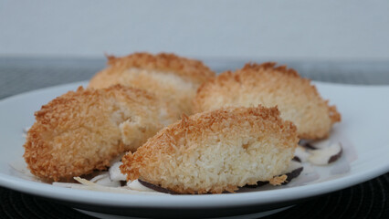 detail of mellow coconut macaroons on a white plate with coconut chips